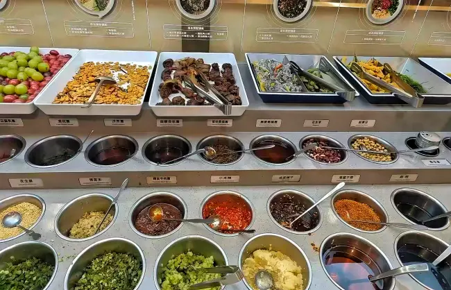dipping sauce diy station of hot pot | China Xian Tour: Private & Tailor-Made China Tours Self-serve salad bar with bowls of chopped vegetables, toppings, and sauces laid out in metal bins.