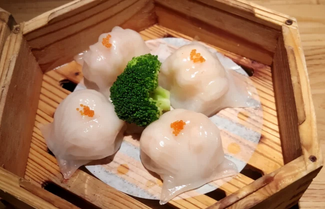 shenzhen-food | China Xian Tour: Private & Tailor-Made China Tours Four translucent steamed dumplings arranged in a wooden steamer with a broccoli floret in the center and small orange roe on top.