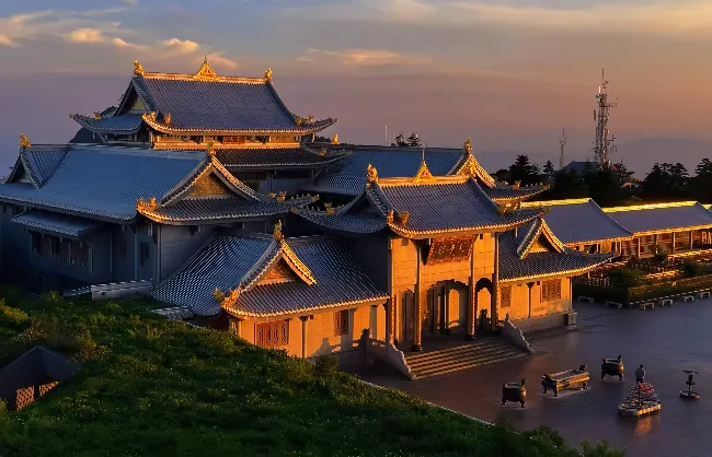 Traditional Chinese-style temple complex with blue-tiled roofs at sunset, ornate gateways and courtyards.
