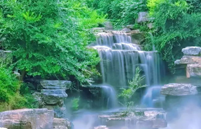 waterfall in xishan national park | China Xian Tour: Private & Tailor-Made China Tours Waterfall cascading over rocky ledges into a misty pool surrounded by green trees and foliage in Beijing Xishan National Park.