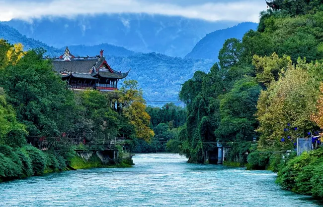 dujiang-november | China Xian Tour: Private & Tailor-Made China Tours Temple pavilion over a turquoise river framed by lush trees and distant mountains.